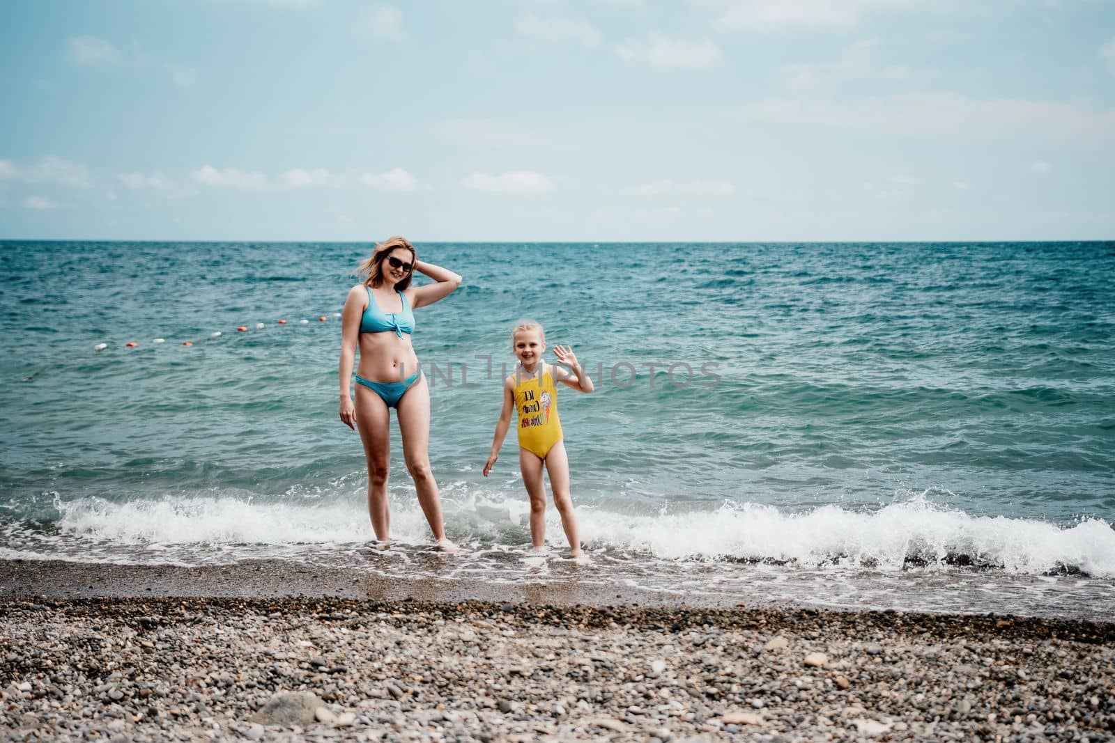 Happy loving family mother and daughter having fun together on the beach. Mum playing with her kid in holiday vacation next to the ocean - Family lifestyle and love concept by panophotograph