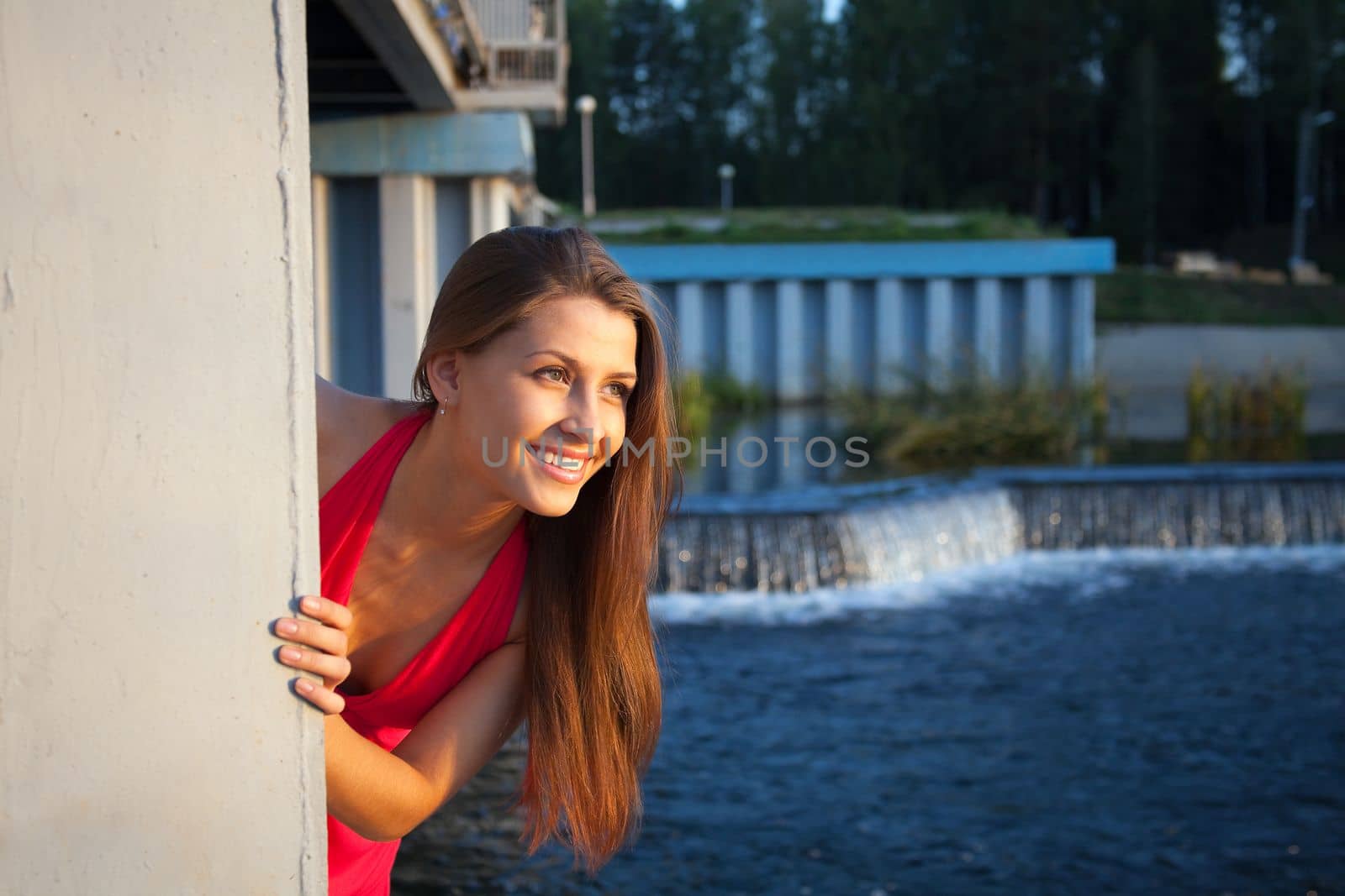Young beauty woman in red near concrete dam look at sunset