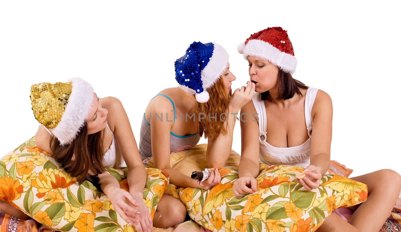 three young woman play on pillows in santa hat