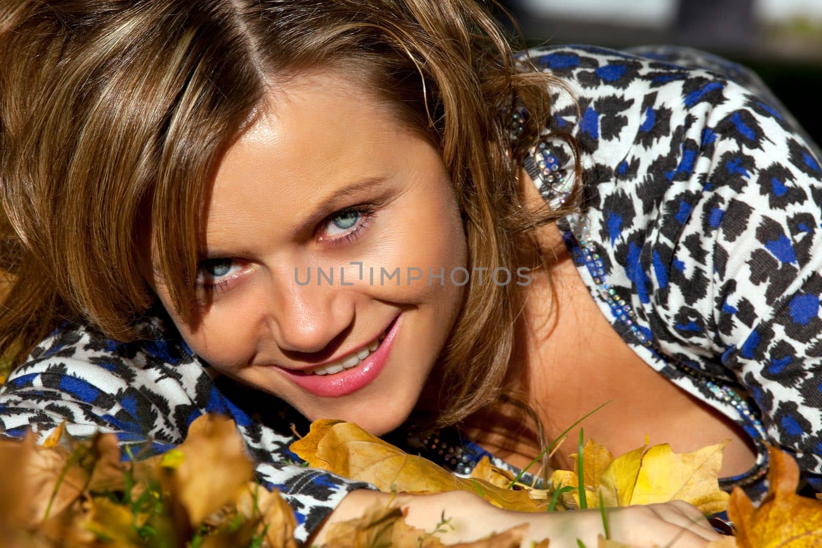 Beauty Woman lay on autumn leaves in sunset and look at you