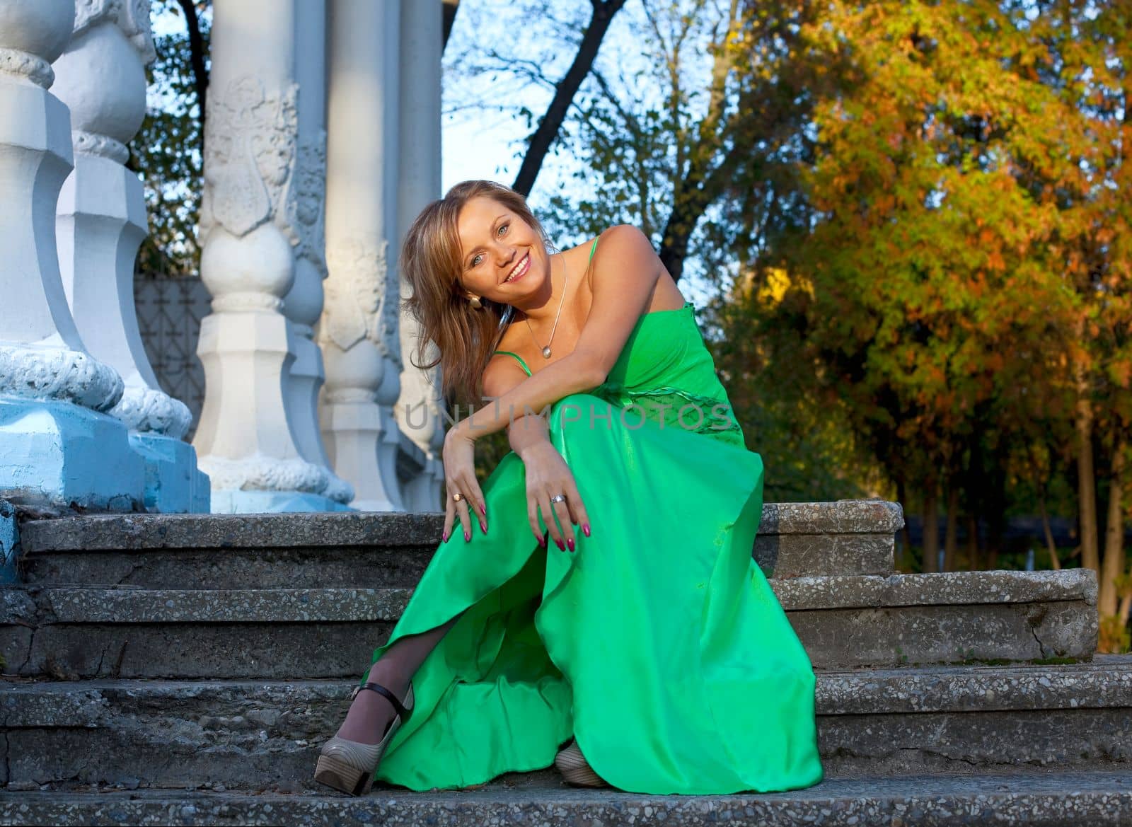 Beauty woman in green clothes sit on stair in autumn park