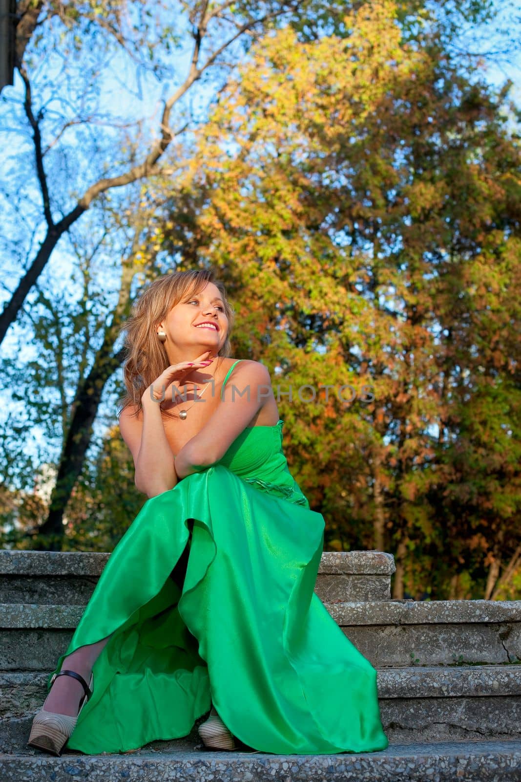 Beauty woman in green clothes sit on stair in autumn park