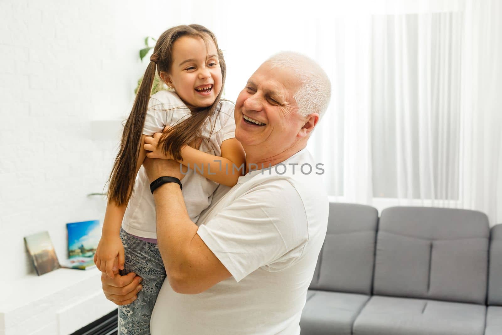 Photo of funny two people old grandpa little granddaughter sitting comfort sofa telling good story stay house quarantine safety modern design interior living room indoors. by Andelov13