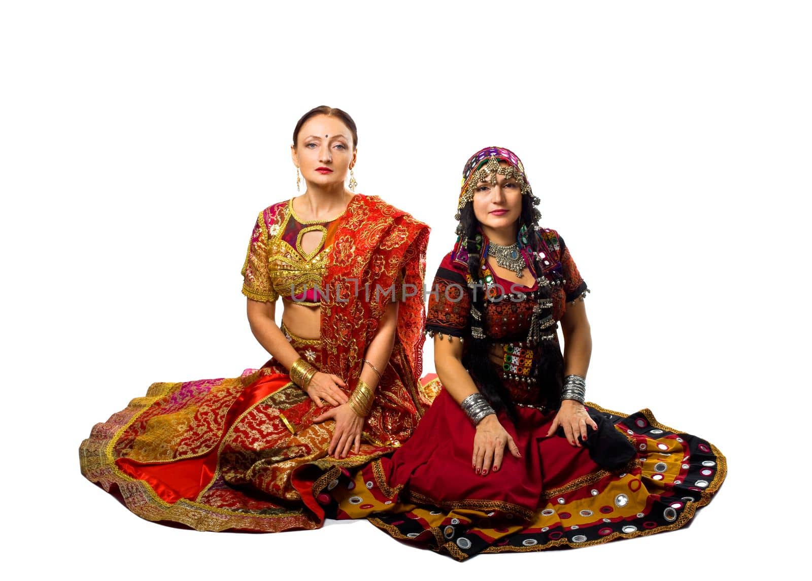 Two woman sit in traditional indian costume by rivertime