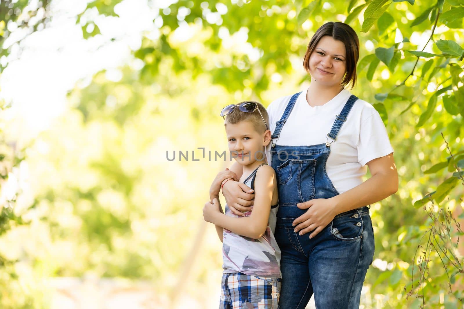 Young and pregnant mother with her son in summer park by Andelov13