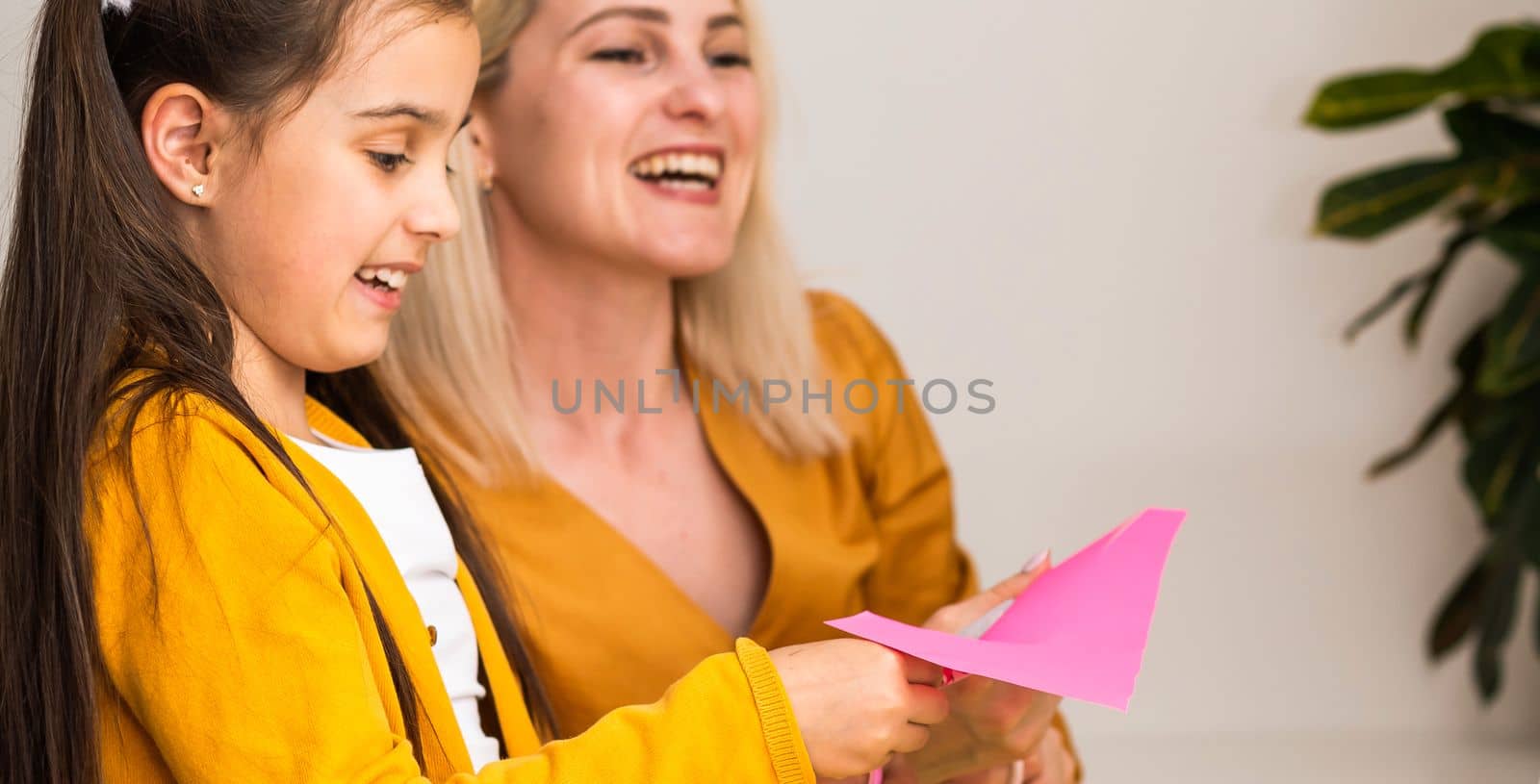 Smiling young Caucasian mom and small daughter sit at home use modern laptop together. Happy mother and little girl child study online talk on video call on computer