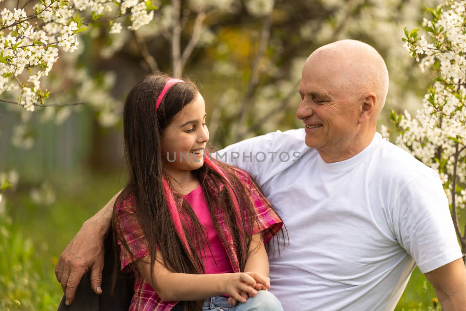 Adorable cute girl and grandfather walk in park