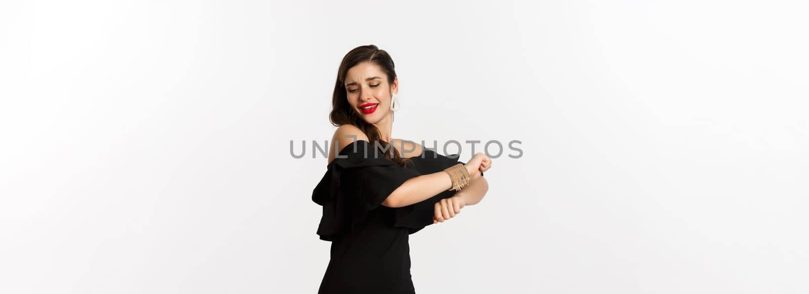 Fashion and beauty. Attractive woman feeling happy and dancing in black party dress, standing carefree against white background.