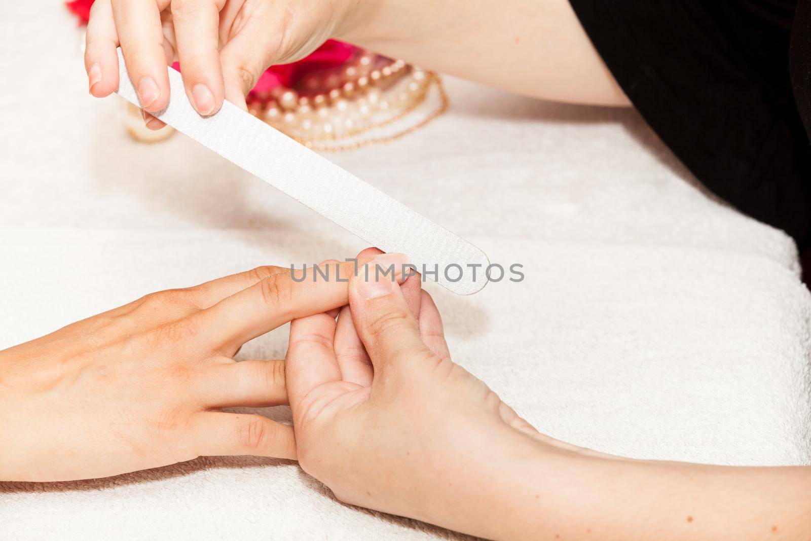 The beautician polish the client's nails before putting nail polish