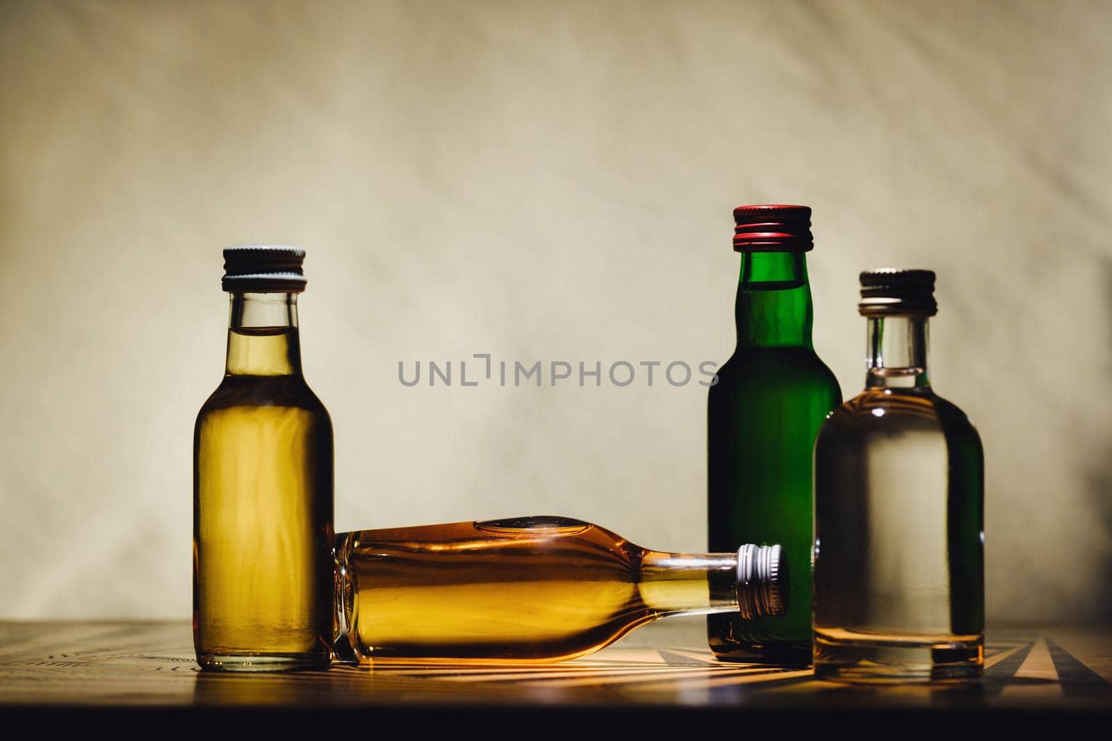 different alcohol bottles are on the table on a light background by Lobachad