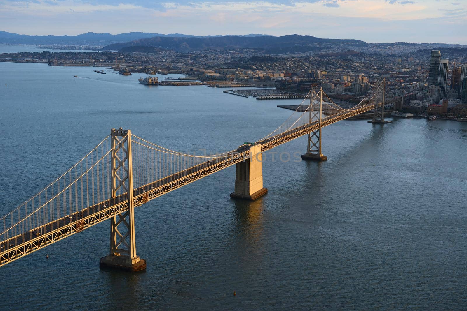 an aerial view of bay bridge near san francisco downtown during sunset, taken from a helicopter 