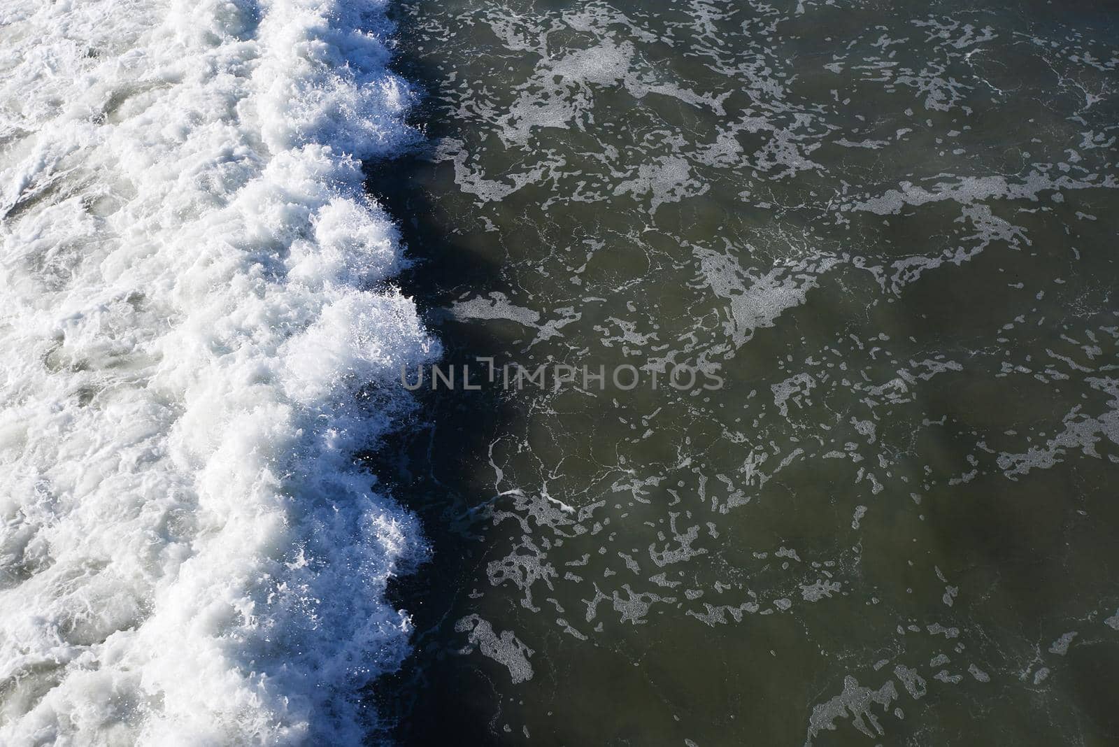 top view of foam of coastal wave when it hit a beach