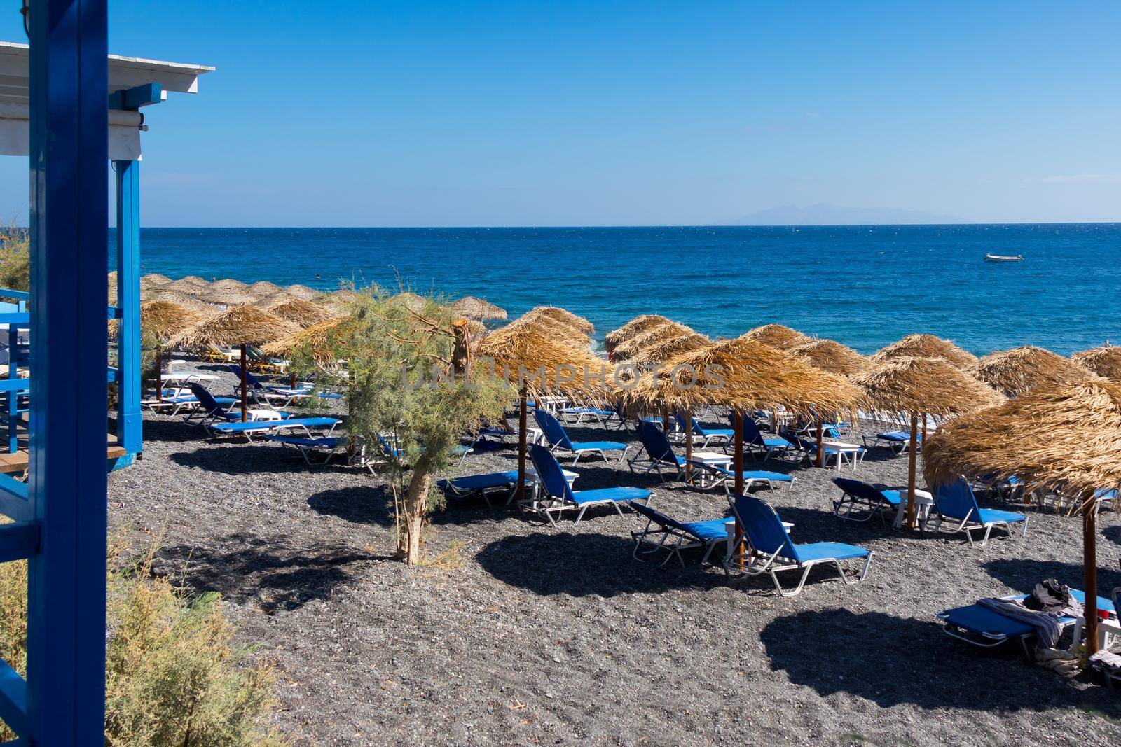 beach with umbrellas and deck chairs in Santorini