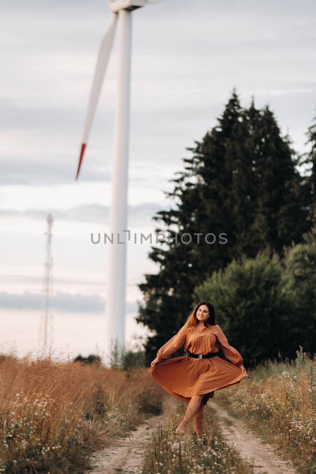 portrait of a Girl in a orange long dress with long hair in nature in the evening