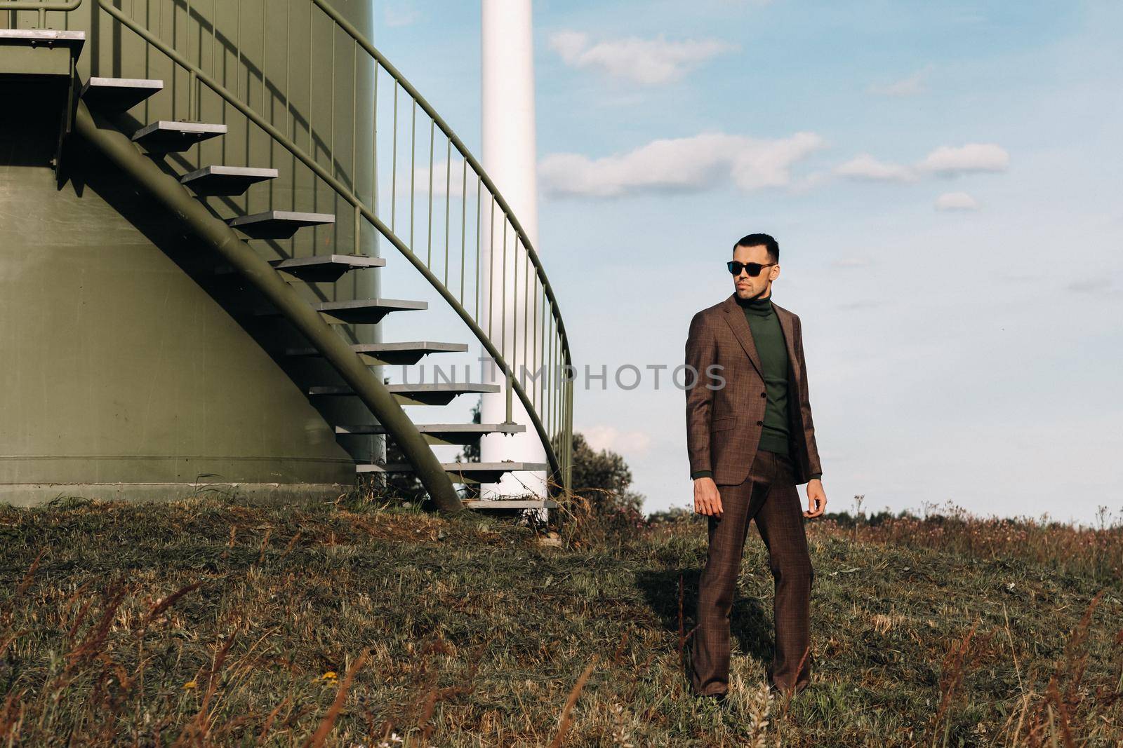 A man in a business suit and green Golf shirt stands next to a green windmill.Businessman near the windmills.Modern concept of the future