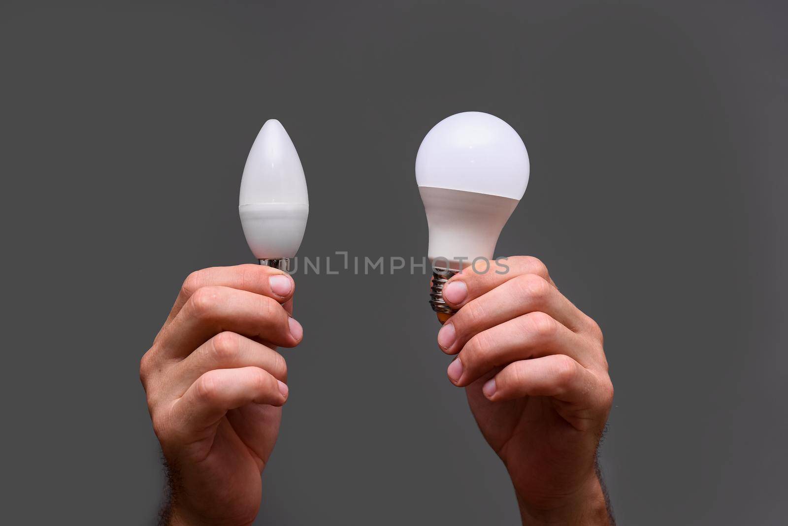 LED lamps of different types in the hands on a gray background. lamps in the form of an arbitrary and candle. Energy efficiency concept and saving electricity