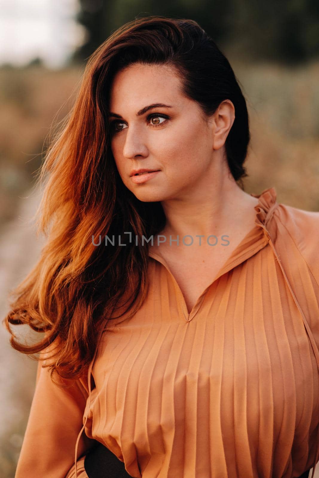 portrait of a Girl in a orangelong dress with long hair in nature in the evening