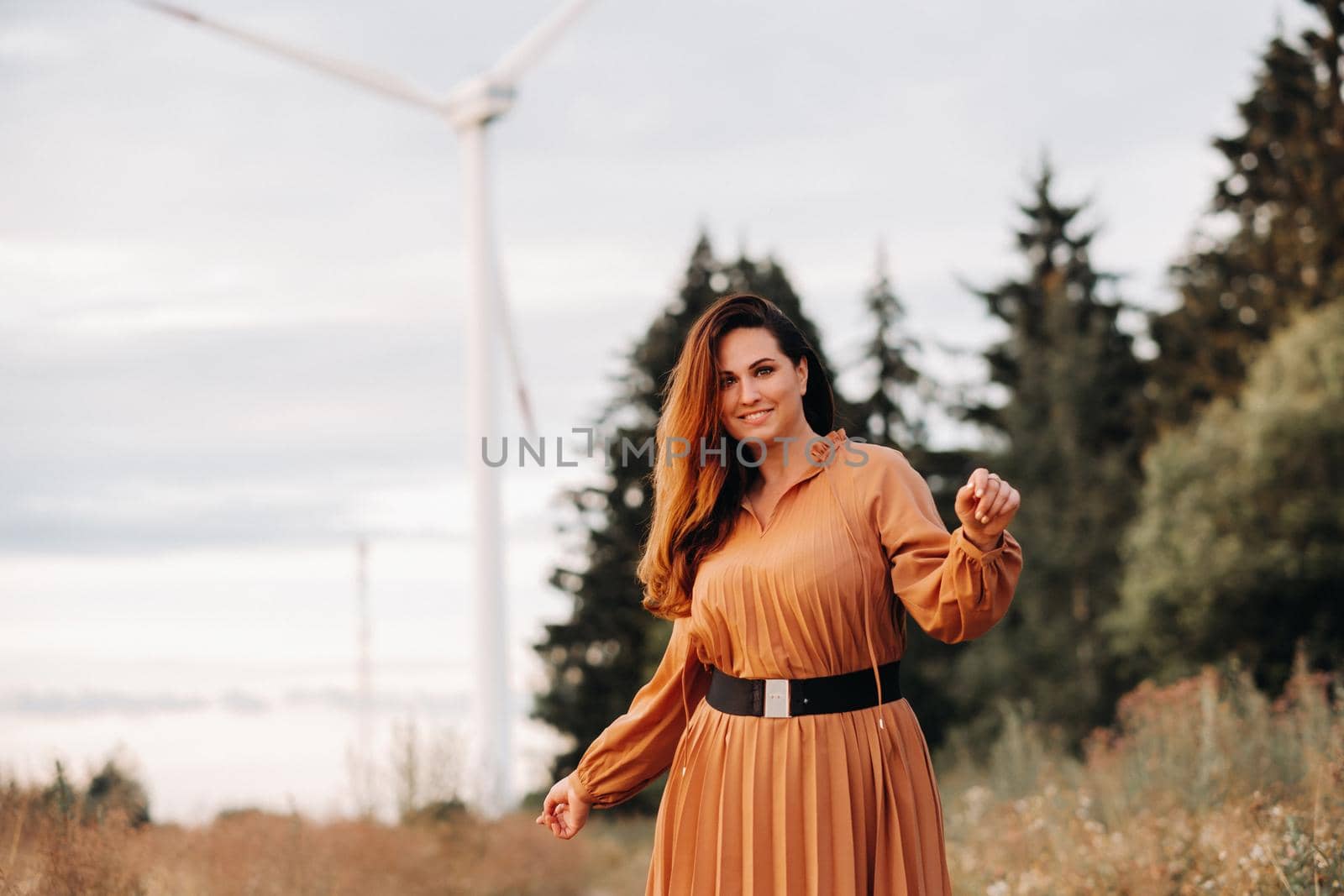 portrait of a Girl in a orange long dress with long hair in nature in the evening