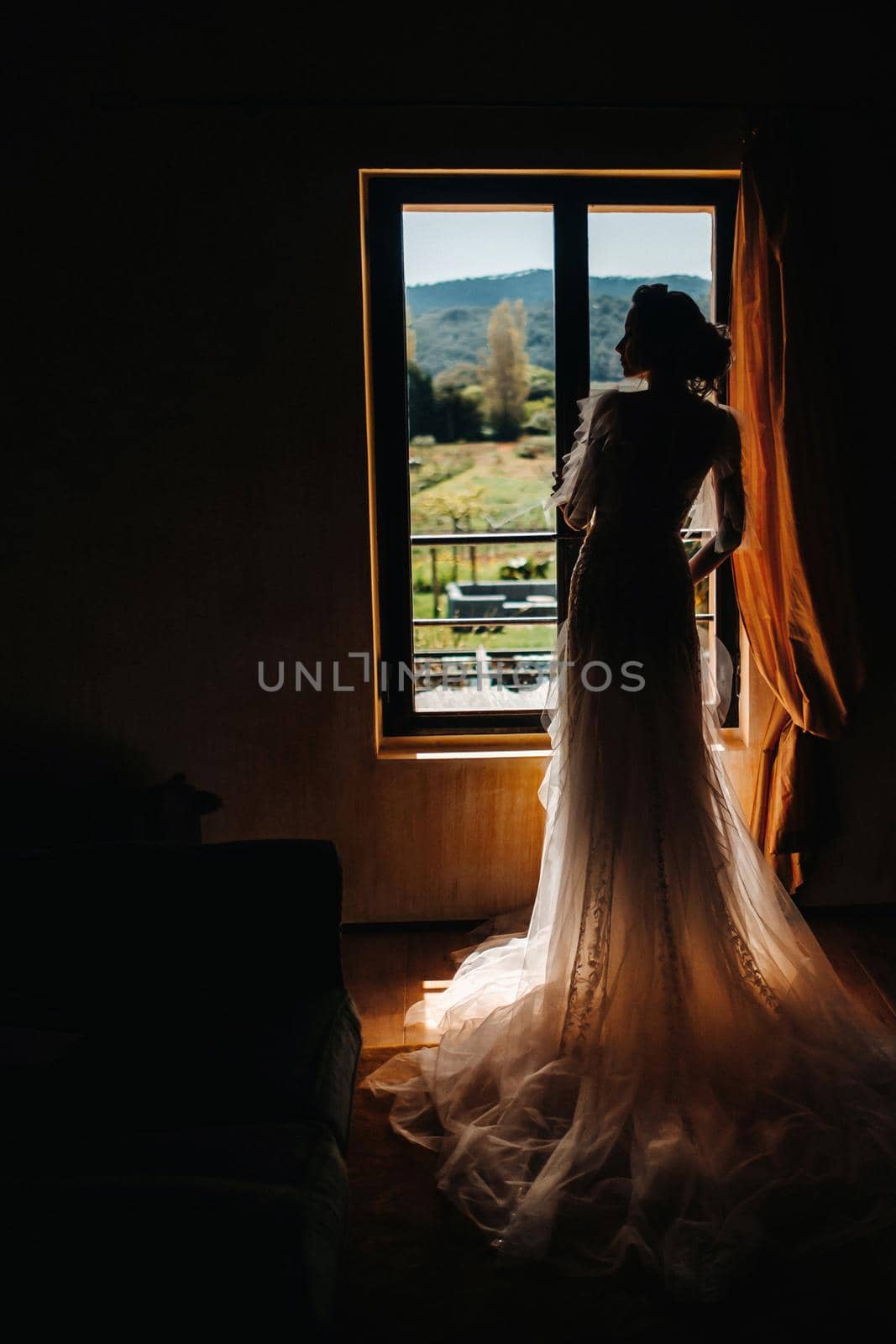 a beautiful bride with pleasant features in a wedding dress poses in the interior of the room. Portrait of the bride in Provence. France by Lobachad