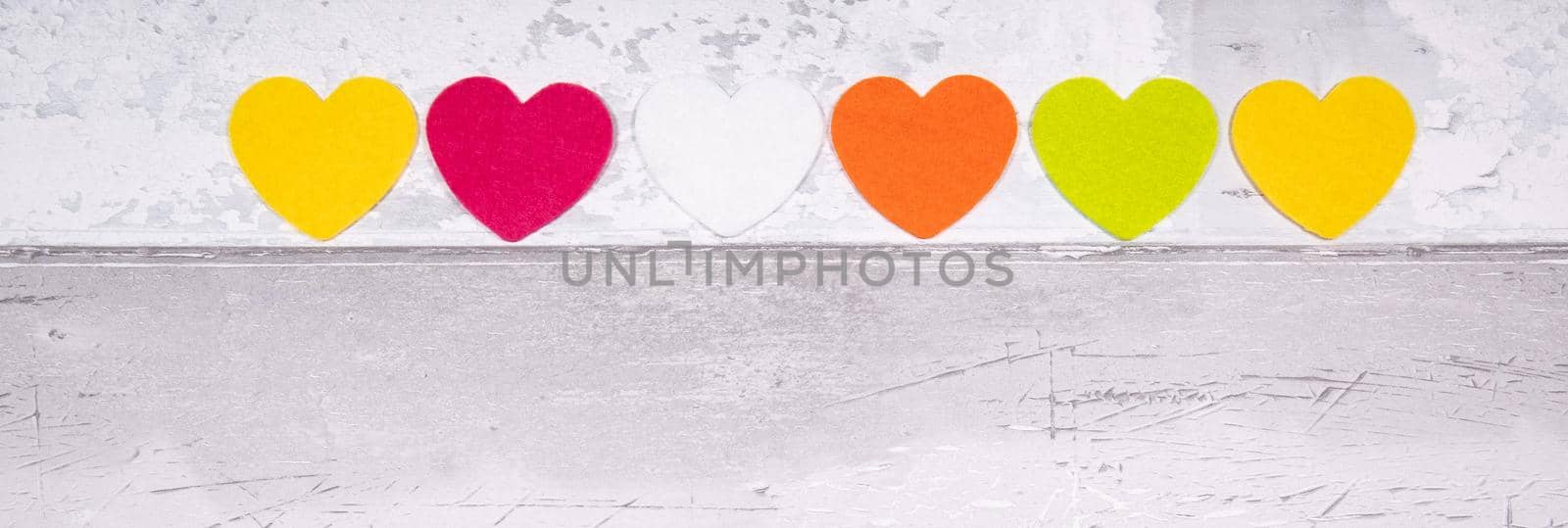 Colorful felt hearts on a background of old wooden planks resembling an old parquet floor. Concept of valentine's day and love in general by jp_chretien
