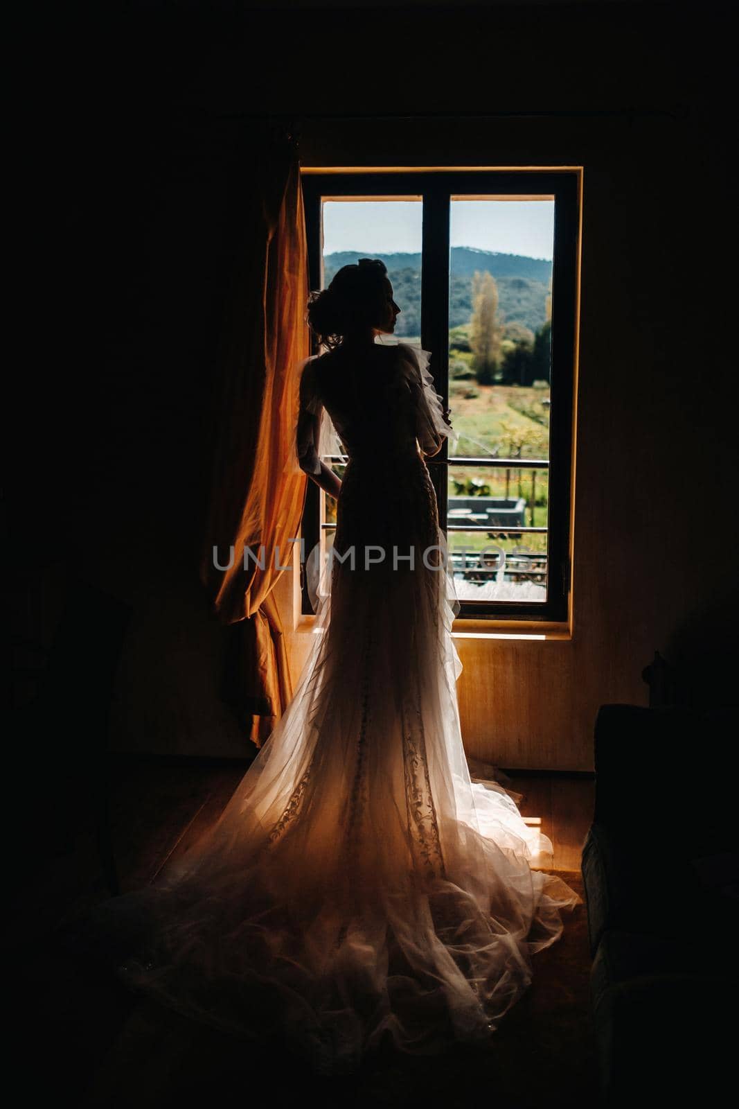 a beautiful bride with pleasant features in a wedding dress poses in the interior of the room. Portrait of the bride in Provence. France by Lobachad