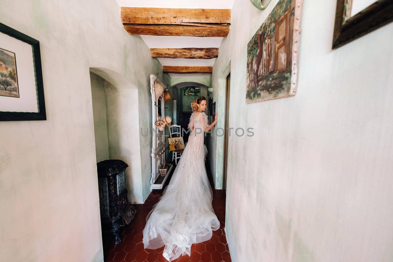 a beautiful bride with pleasant features in a wedding dress poses in the interior of the room. Portrait of the bride in Provence. France by Lobachad