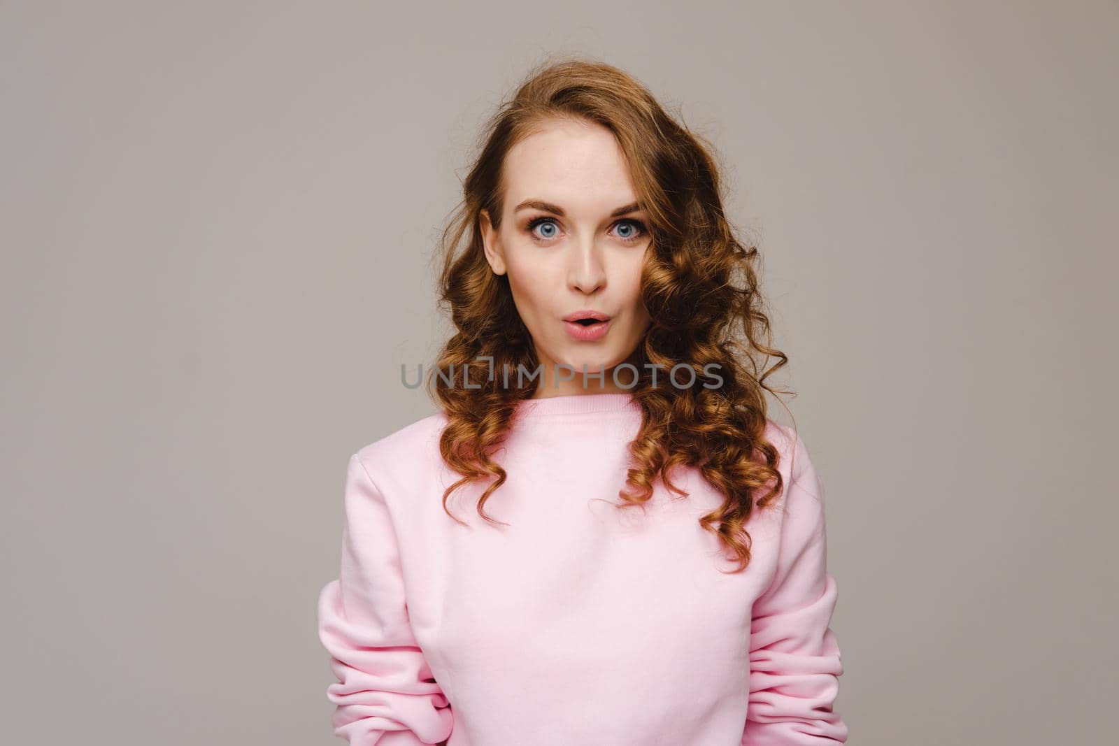 A beautiful girl on a gray background expresses her emotions, a woman with emotions.
