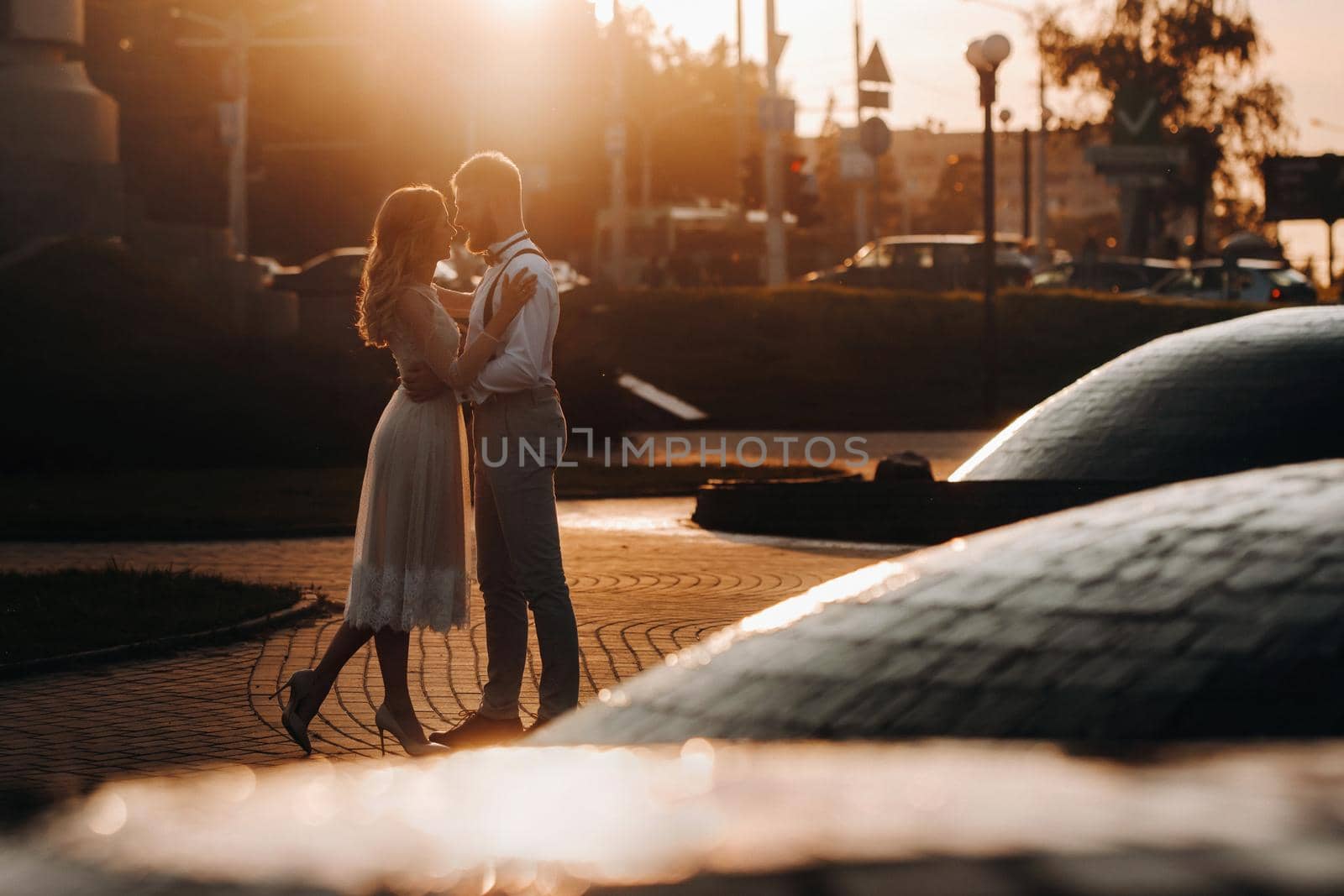a young couple embraces in the city at a beautiful sunset, urban style by Lobachad