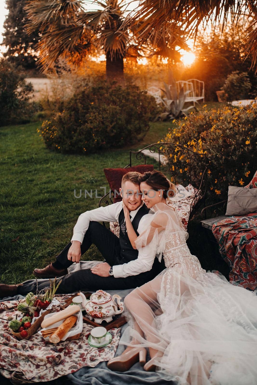 Dinner the Bridal couple at the picnic.A couple is relaxing at sunset in France.Bride and groom on a picnic in Provence. by Lobachad