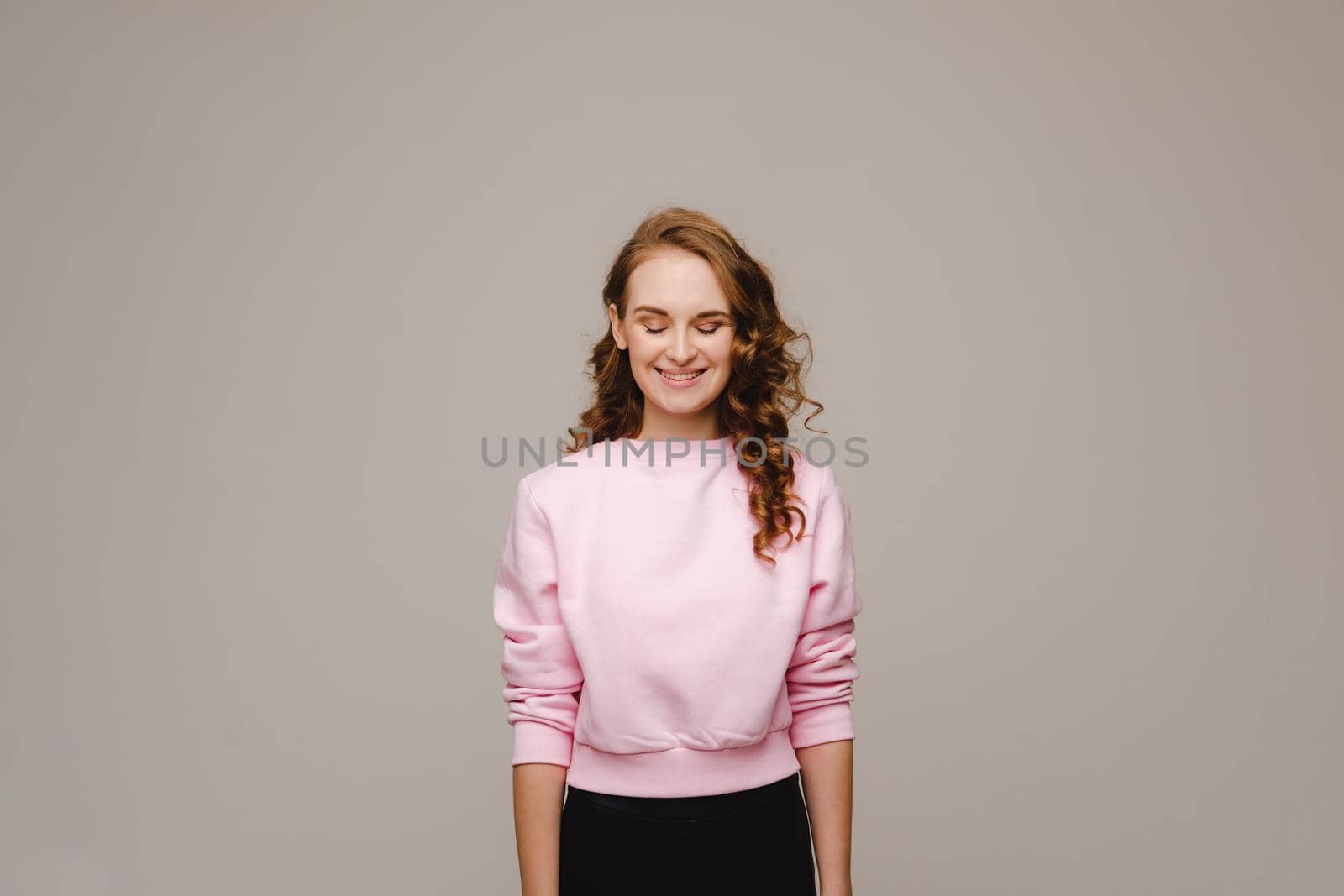 A beautiful girl on a gray background expresses her emotions, a woman with emotions.