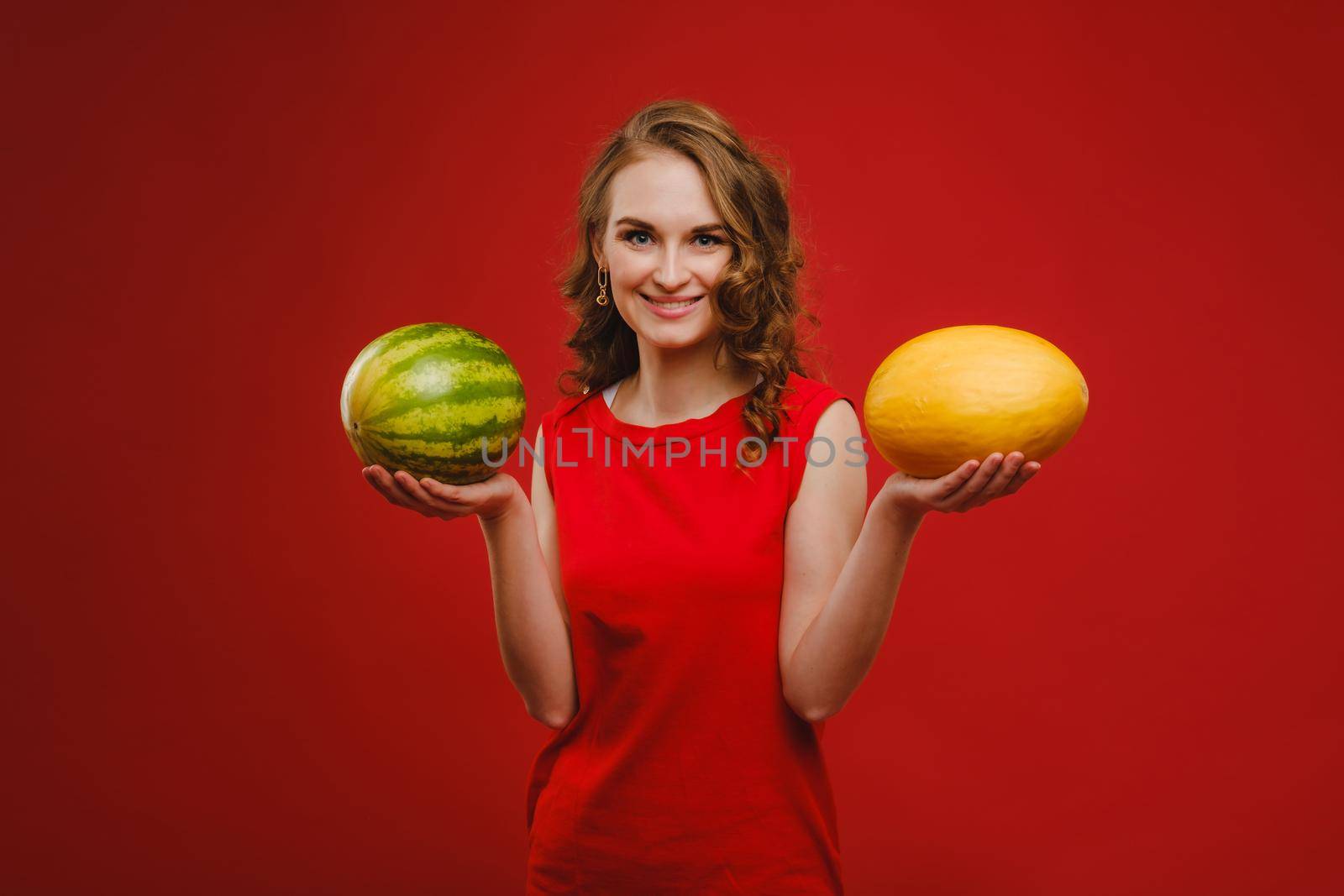 Photo of wavy cheerful curly casual positive cute nice charming pretty girlfriend smiling toothily having fetched you a watermelon isolated over vivid orange color background.