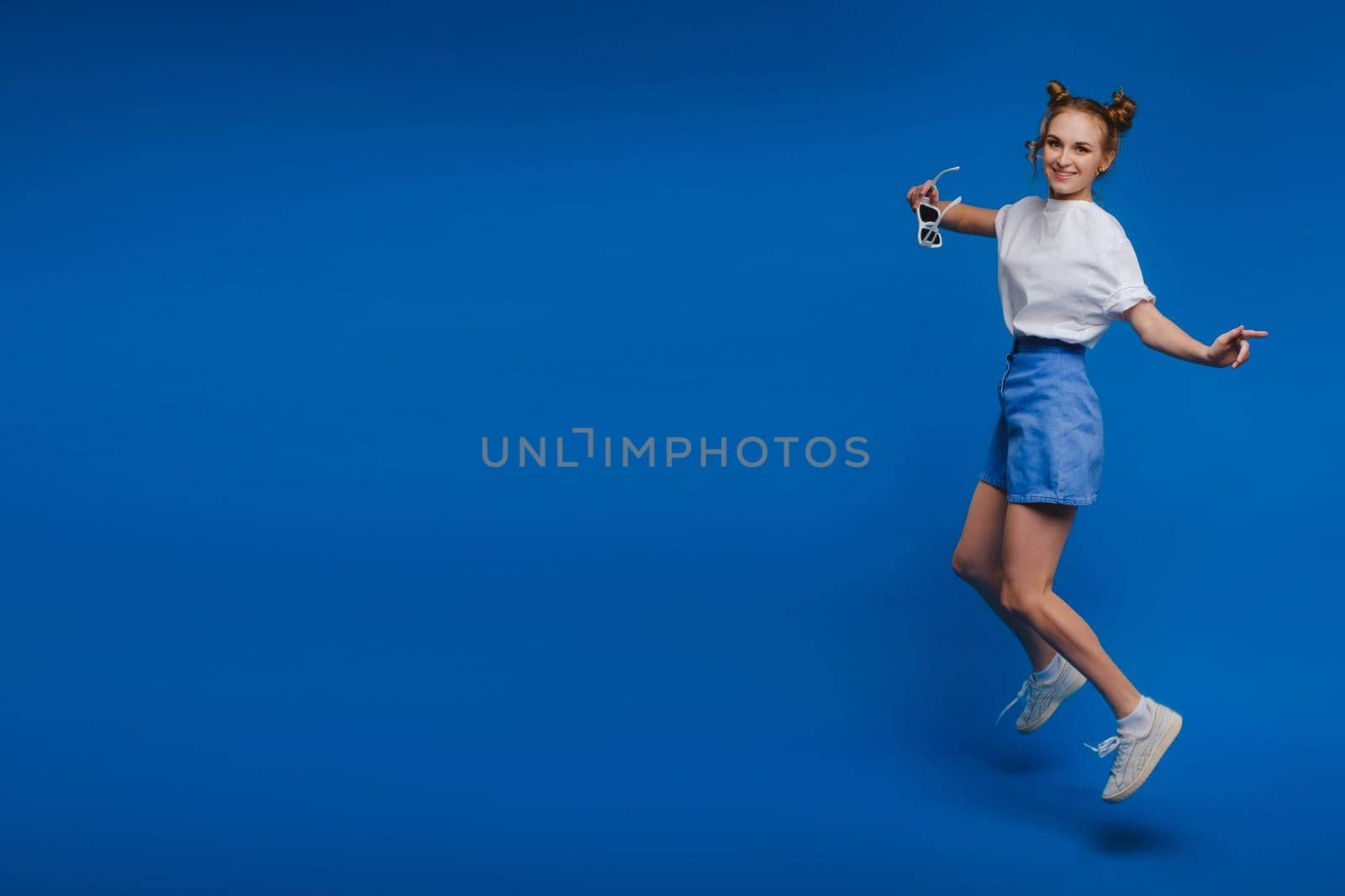 happiness, freedom, motion and people concept - smiling young woman jumping in air over white background.