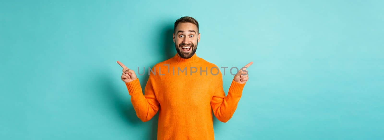 Shopping and advertisement concept. Excited man buyer pointing fingers sideways, showing two choices products, left and right banners, standing over light blue background.