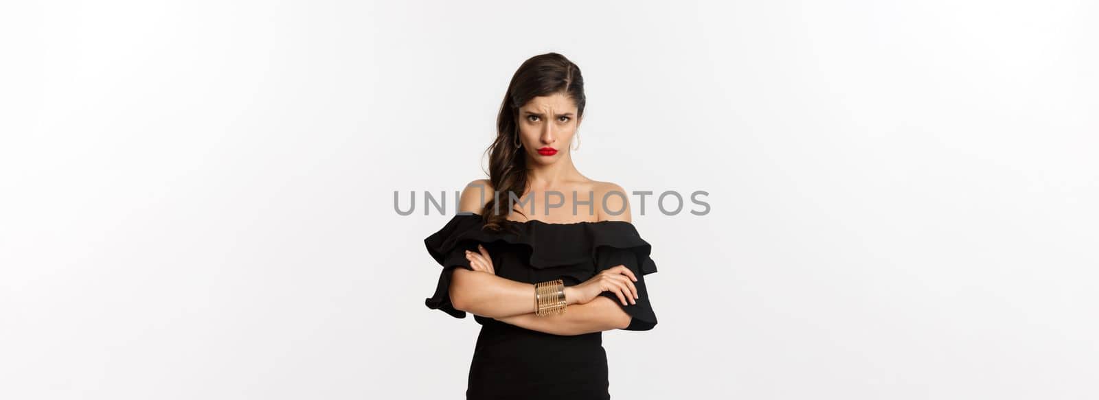 Fashion and beauty. Cute sulking girlfriend feeling offended, looking from under forehead with arms crossed, angry at person, standing over white background by Benzoix