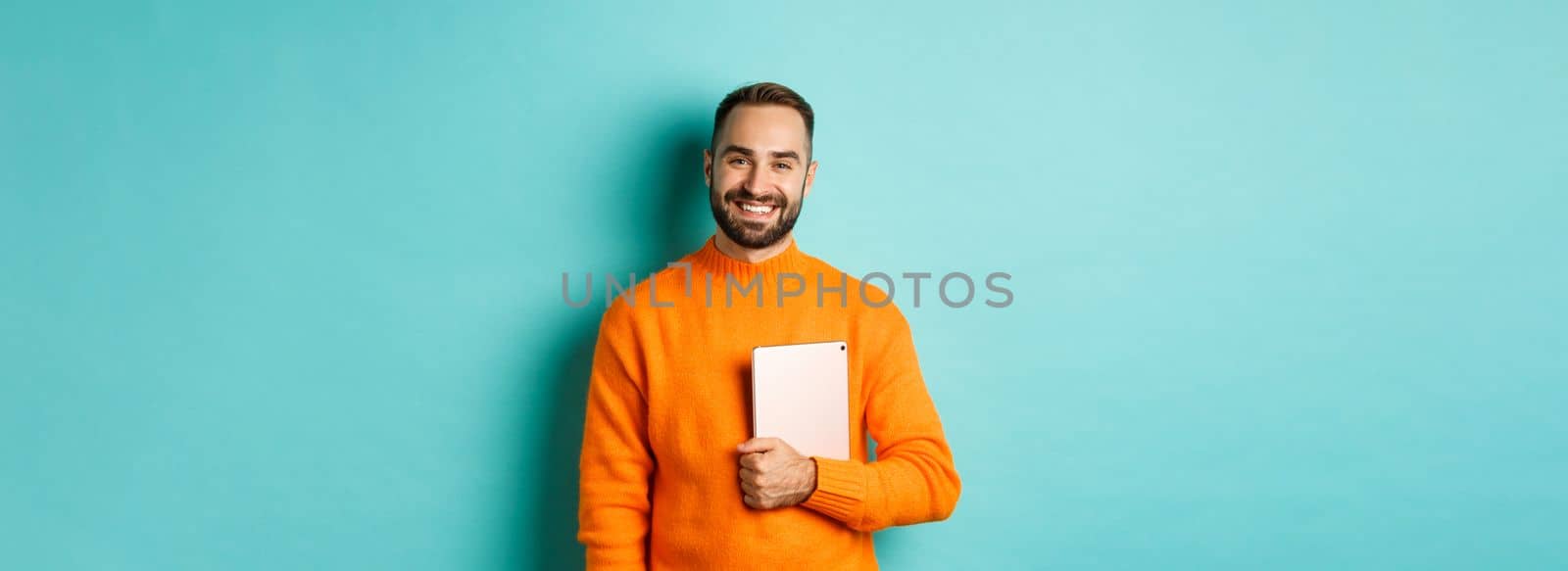 Handsome freelancer man holding laptop and smiling, standing happy over light blue background by Benzoix