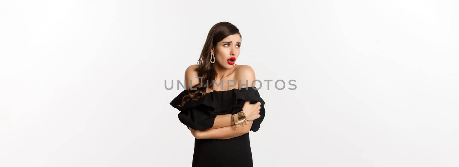 Image of scared and shocked glamour woman looking around, comfort herself, standing alarmed against white background by Benzoix