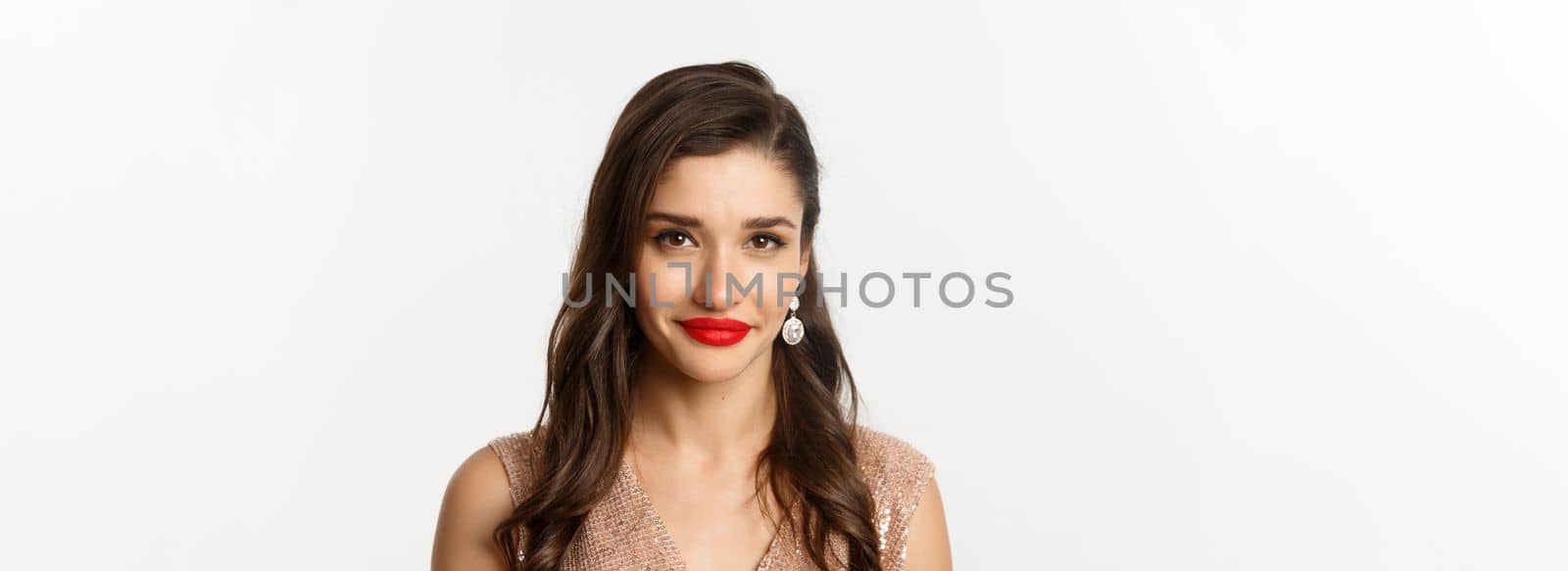 Close-up of attractive woman with hairstyle and red lips, standing in elegant dress and smiling, celebrating Christmas party, standing over white background.