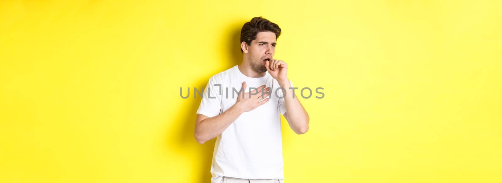 Image of man with covid-19 or flu symptoms, coughing and feeling sick, standing over yellow background by Benzoix