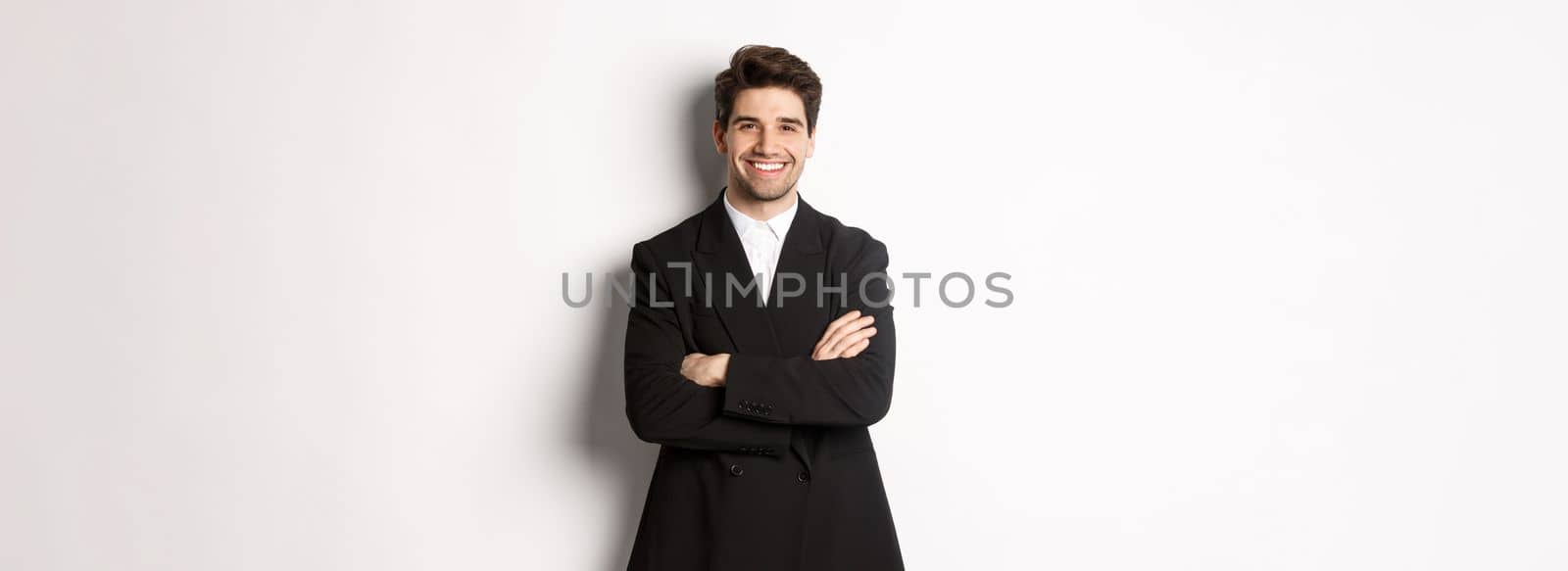 Handsome and confident bearded man, standing in formal suit with hands crossed on chest, smiling satisfied, attend party or work event, standing over white background by Benzoix