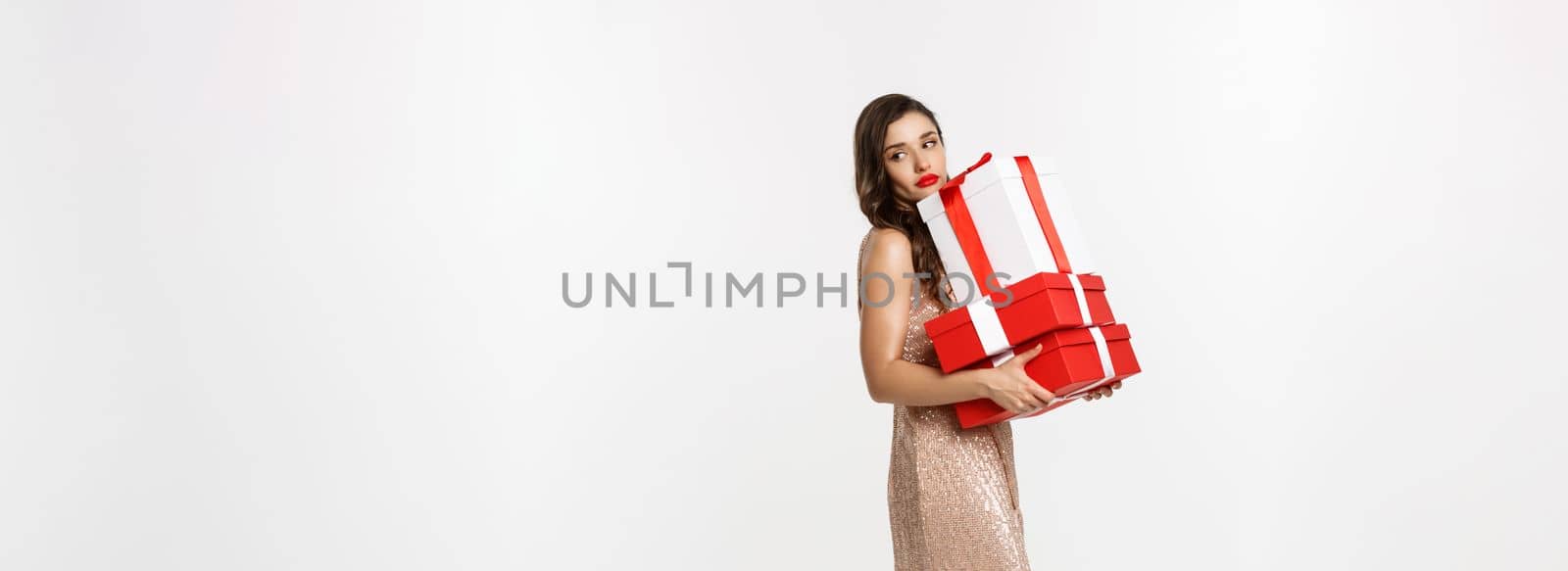 Party and celebration concept. Full-length of attractive glamour woman in elegant dress, holding Christmas gifts and looking tired, white background.