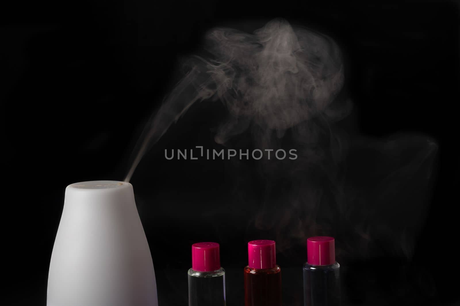 aroma humidifier steaming with scent pots isolated on a black background