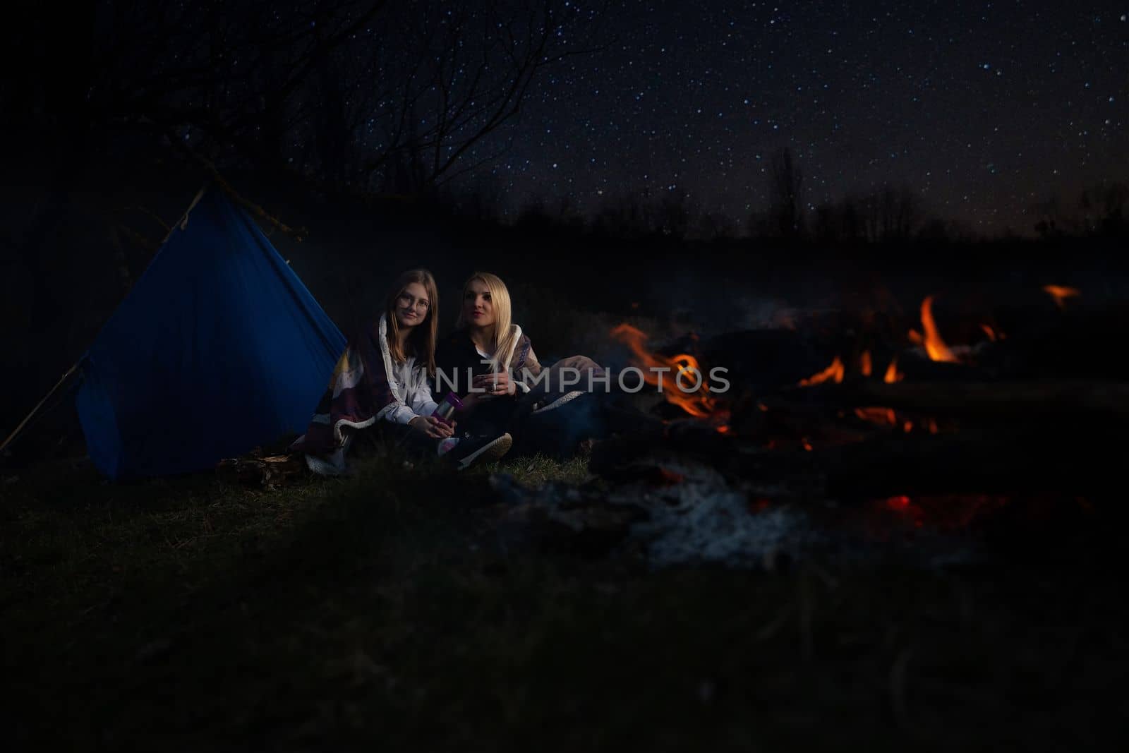 The family, mother and daughter, for the weekend went out into the countryside for a picnic, sit by the fire in the wild with a tent, fry potatoes, drink hot tea. High quality photo