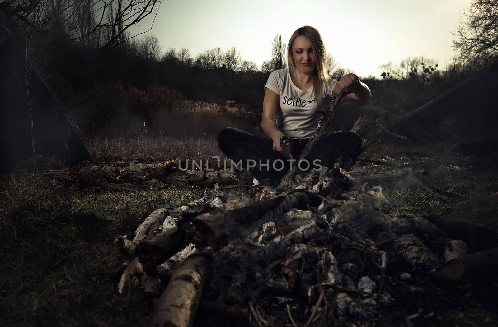  A girl cuts wood for a fire at a picnic. High quality photo