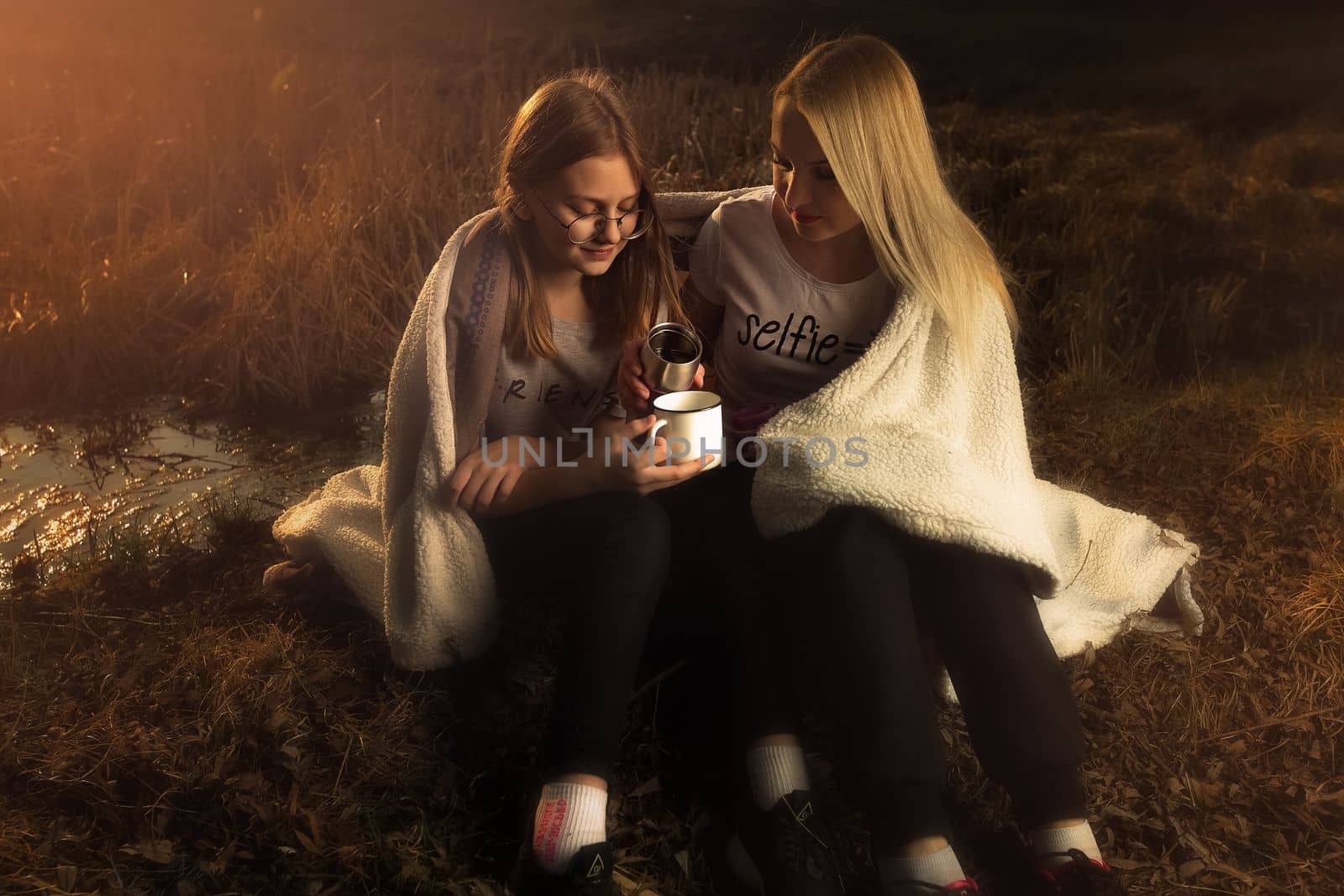 The family, mother and daughter, for the weekend went out into the countryside for a picnic, sit by the fire in the wild with a tent, fry potatoes, drink hot tea. High quality photo