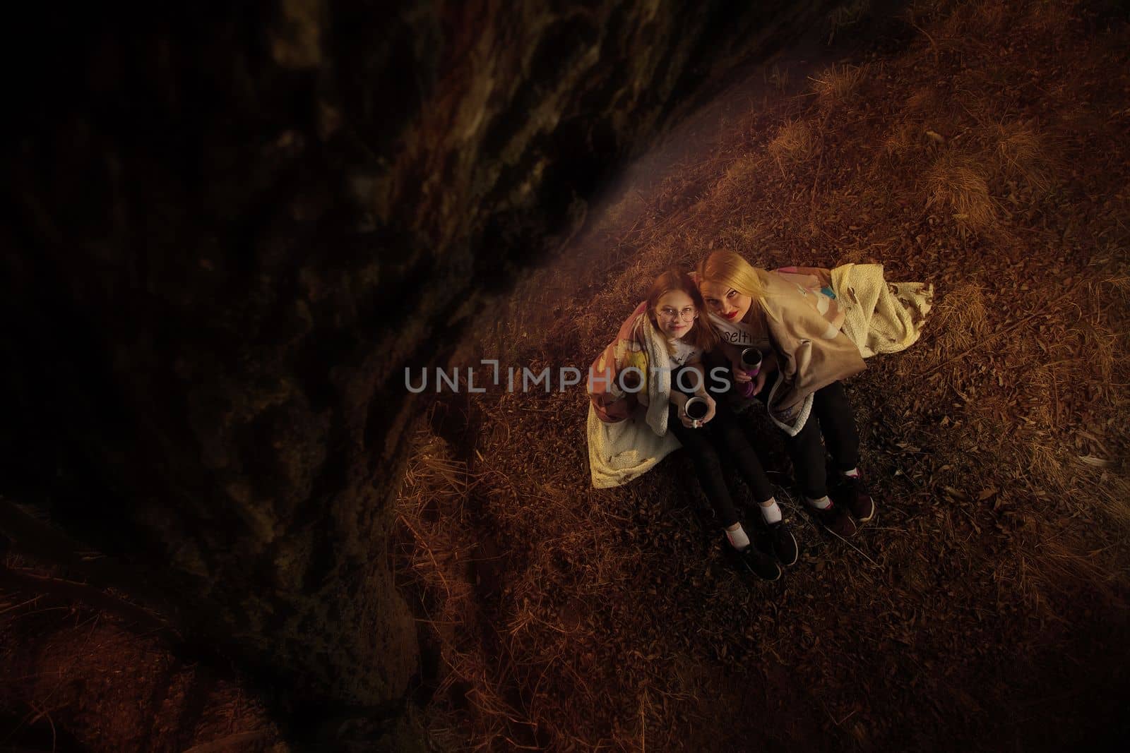The family, mother and daughter, for the weekend went out into the countryside for a picnic, sit by the fire in the wild with a tent, fry potatoes, drink hot tea. High quality photo