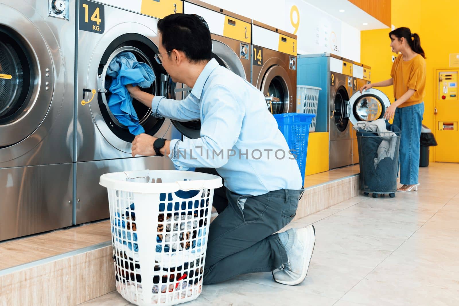 Asian people using qualified coin operated laundry machine in the public room to wash their cloths. Concept of a self service commercial laundry and drying machine in a public room.