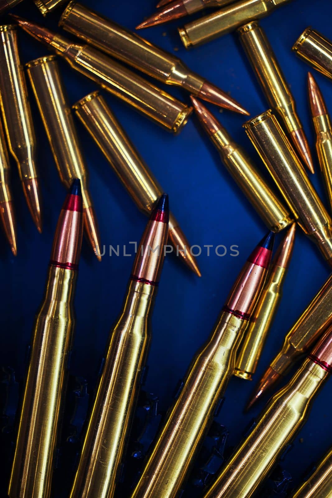 Ammunition for the machine gun and rifle are scattered on the table. Ammonution on dark blue table. Ammo pile, war ammo background by EvgeniyQW