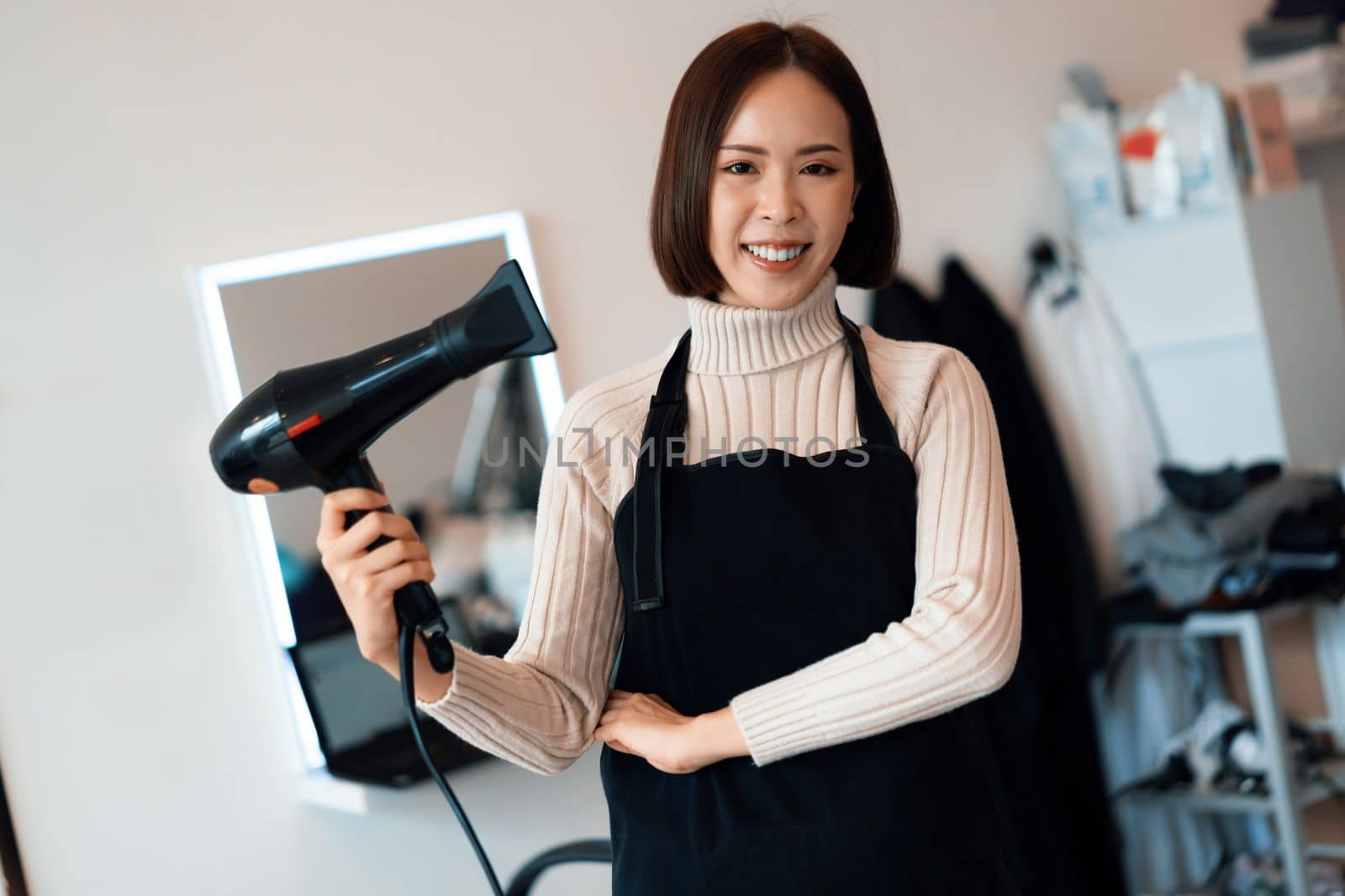 Portrait of a young asian female hairdresser holding qualified haircut tools in her salon for a woman's haircut. Photo job concept for small business owner and haircare.