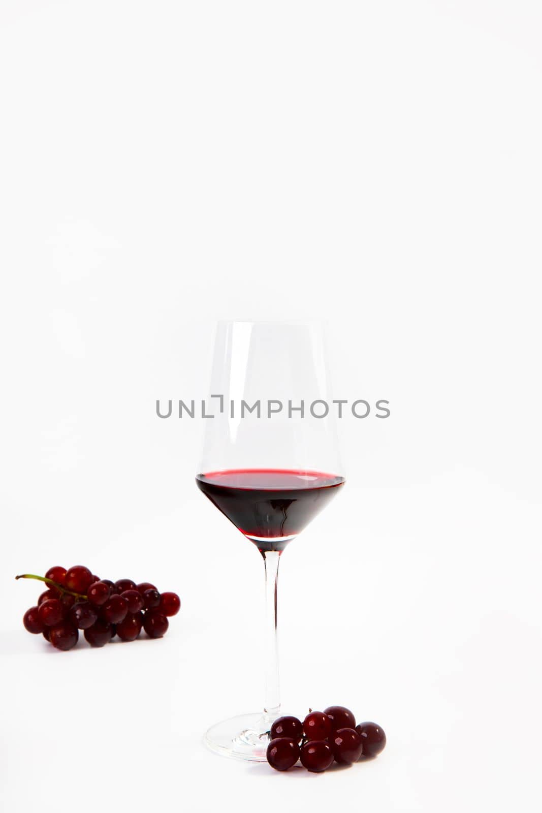 Wine glass with a splash of red wine and grapes isolated on white background copy space luxury