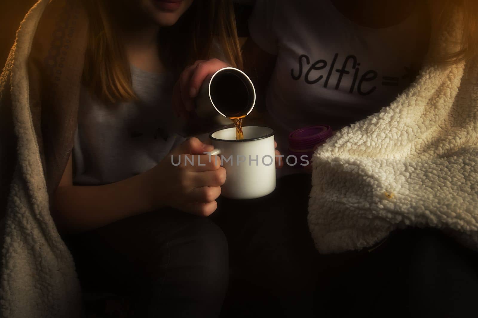 The family, mother and daughter, for the weekend went out into the countryside for a picnic, sit by the fire in the wild with a tent, fry potatoes, drink hot tea. High quality photo